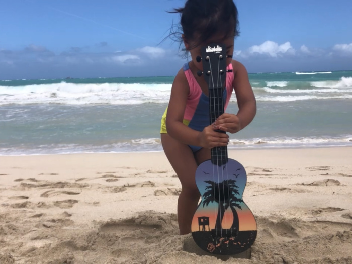 child at beach with ukulele
