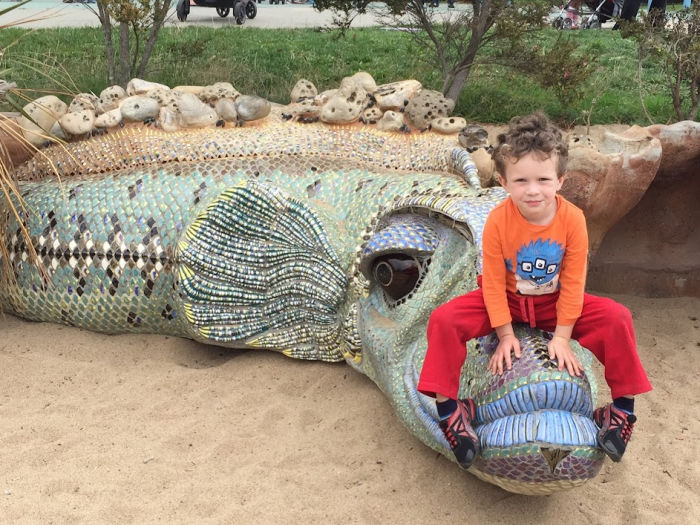 child climbs on a dragon sculpture