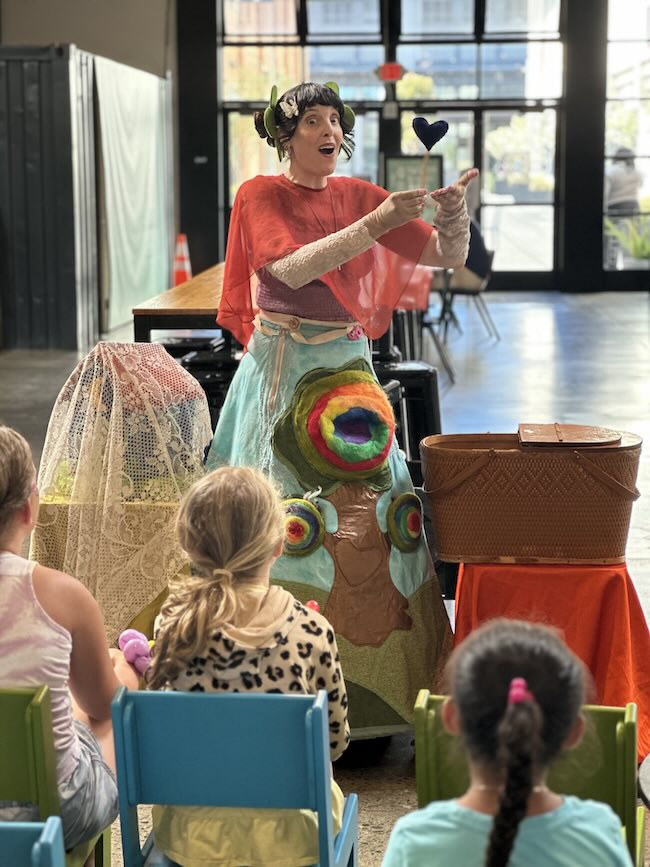 children's entertainer, a fairy, and the backs of children at a wide open space