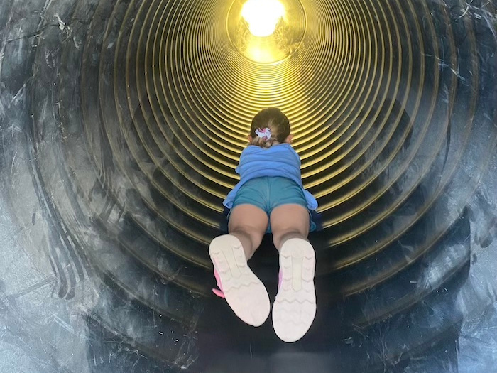 girl sliding down a tube slide