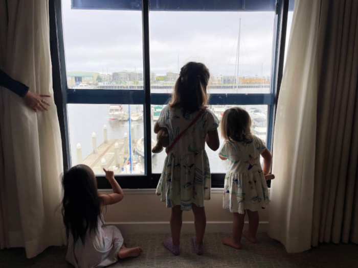 3 girls look out the window at the oakland marina