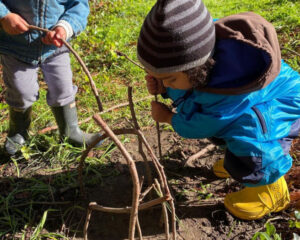 toddler building with sticks in the dirt
