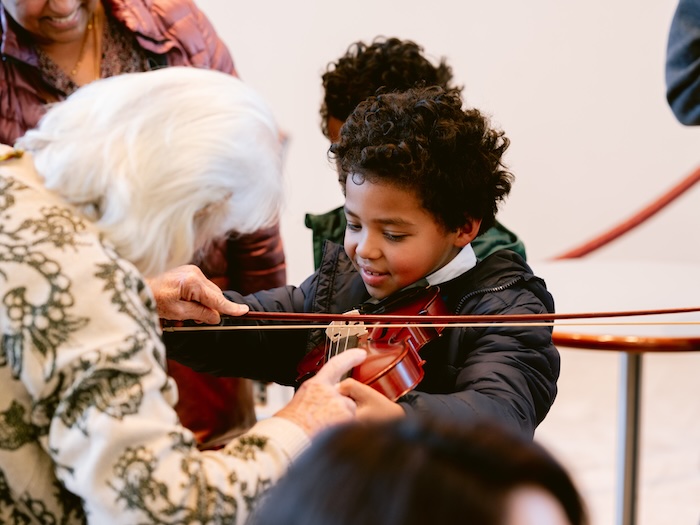 child playing violin wiht help from an adult