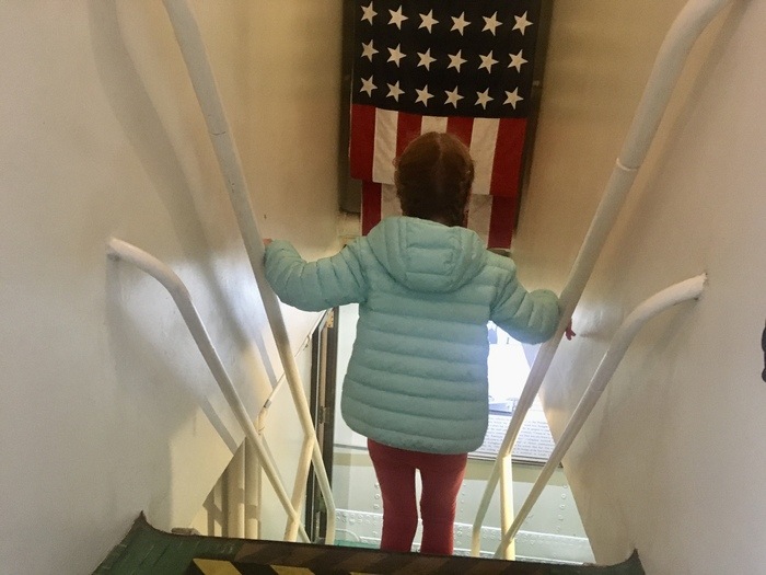 Child climbs down stairs with American flag in background