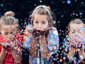 3 young girls blowing confetti