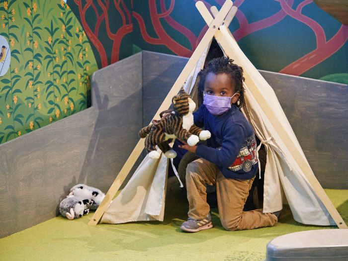 Child playing in playtent with stuffed animals