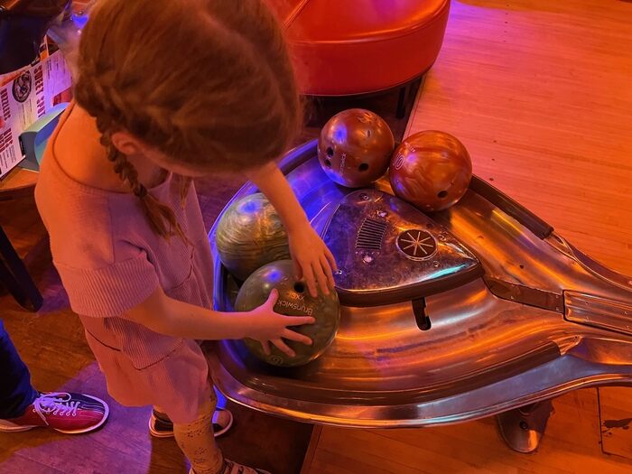 Child picking up bowling ball