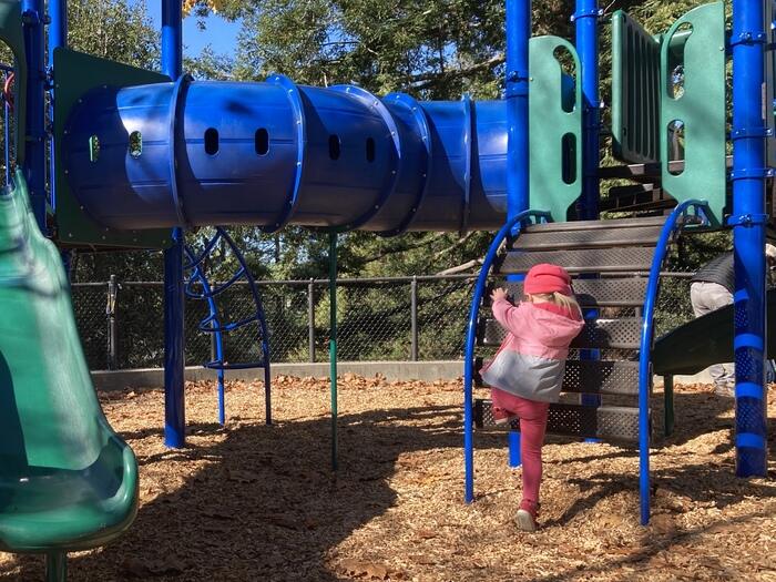 Child climbs on playground in Kensington, CA
