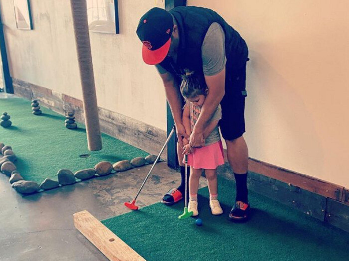 Father and daughter mini golfing indoors