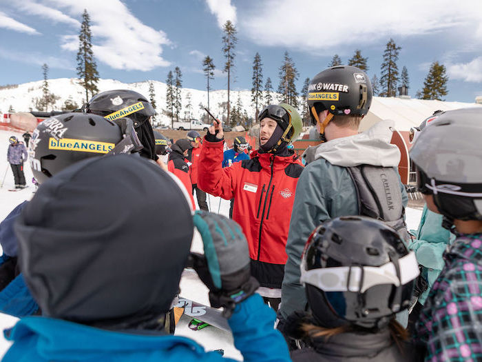 ski instructor talking to a bunch of kids in snow gear