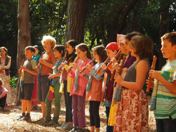 children outdoors playing flutes