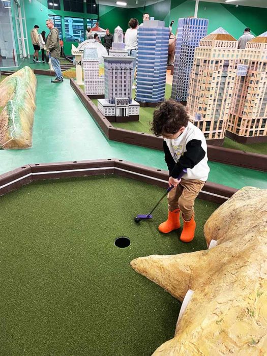 little kid plays mini golf