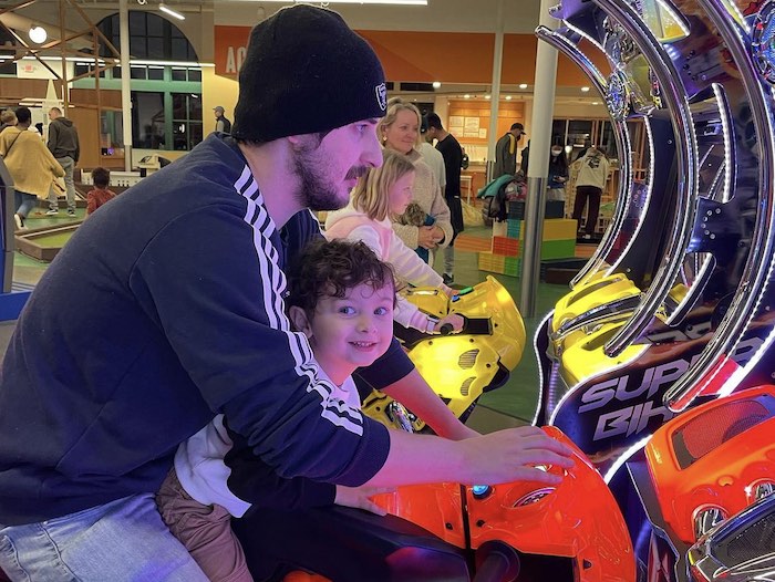 kid and dad do a ride on video game at subpar mini golf