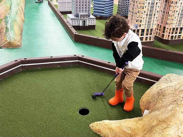 Child mini golfs at indoor course