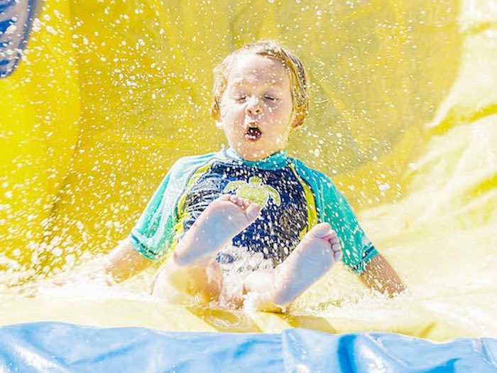 Child Riding Bladium Bouncy Waterslide at Spring Camp