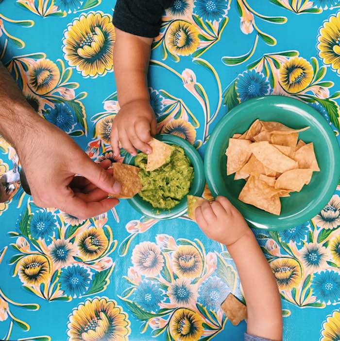 kids and adult grabbing chips and guac at cholita linda restaurant