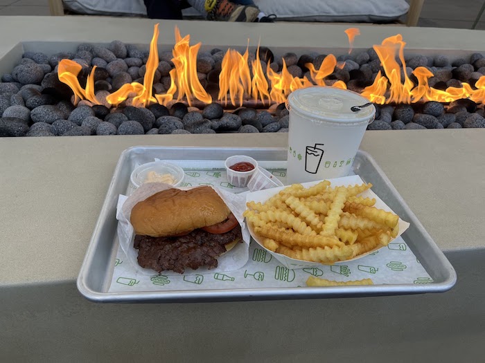 Burger, fries, & shake by the fire pit at Bay Street Bay Break Terrace