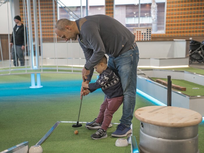 Father and son playing mini golf together at Tipsy Putt