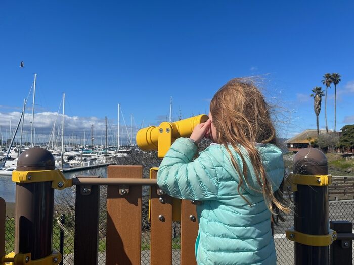 Child looking through play telescope at playground