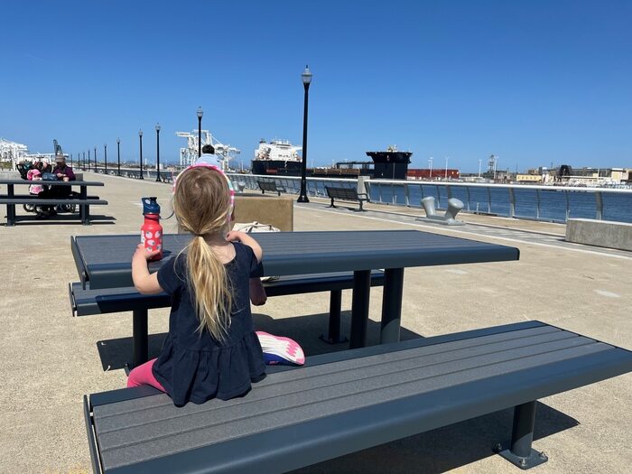 Child eating snack at picnic table along waterfront
