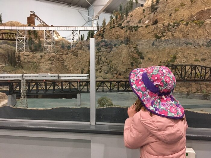 Child excitedly looks at model trains passing by