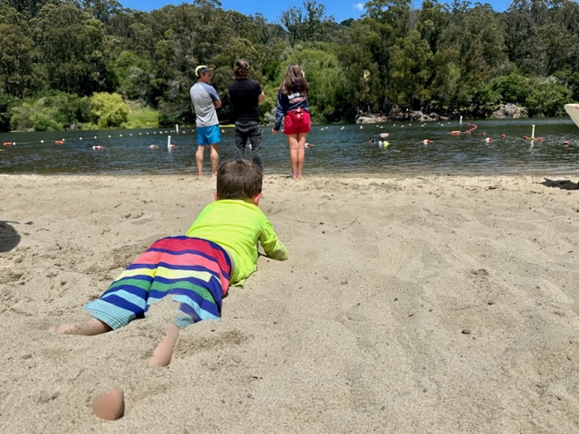 little boy laying in sand on beach
