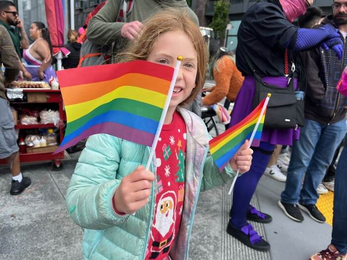 Child holds rainbow flags