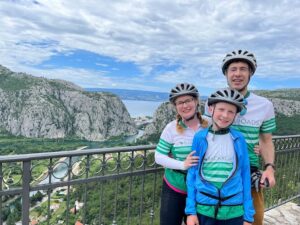 two adults and one child wearing bike clothes stand in front of an overlook