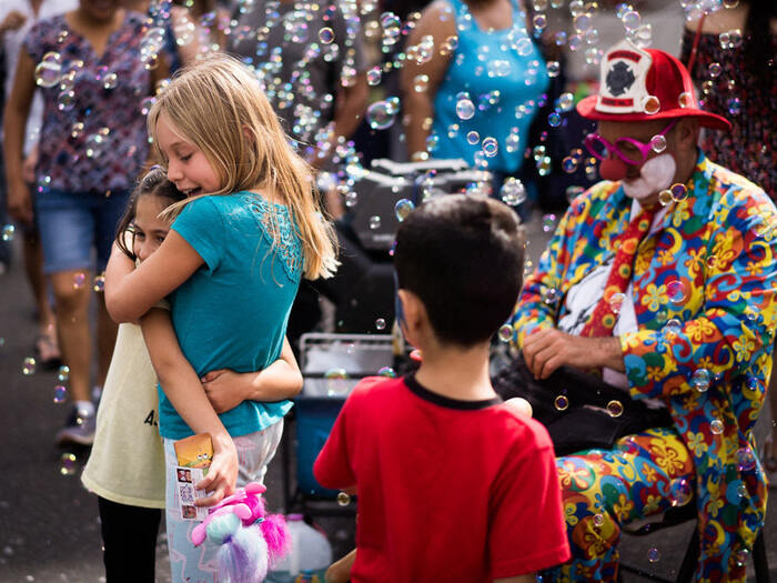 Children hug while bubbles drift through air at community festival