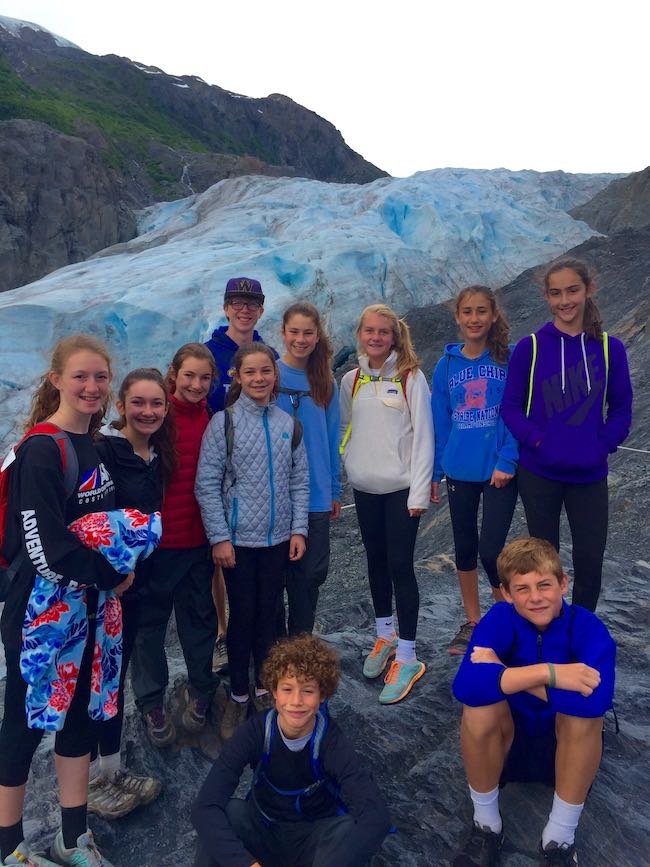 several kids and teens sitting on a glacier