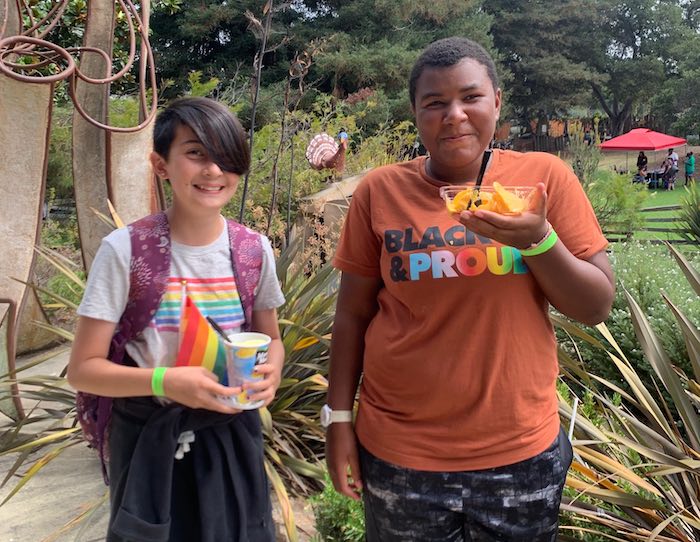 Fairyland Pride FairyProud guests two kids wearing rainbow pride garb with treats at children's fairyland