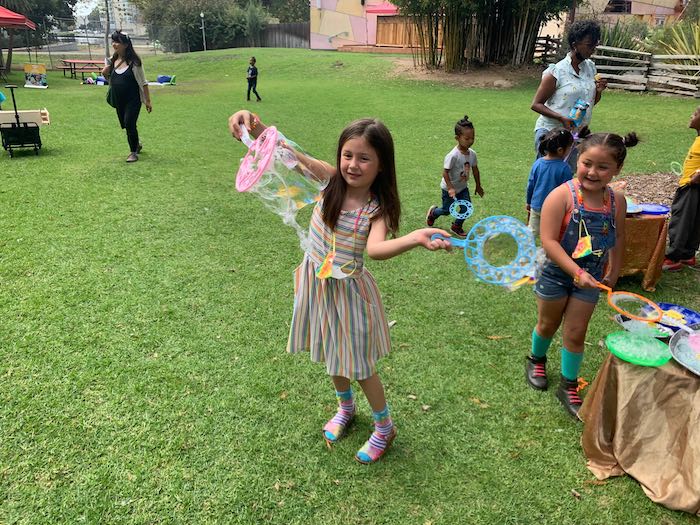 children and adults blow colorful bubbles on the fairyland lawn
