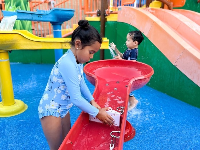 two kids doing water play on a colorful sprayground