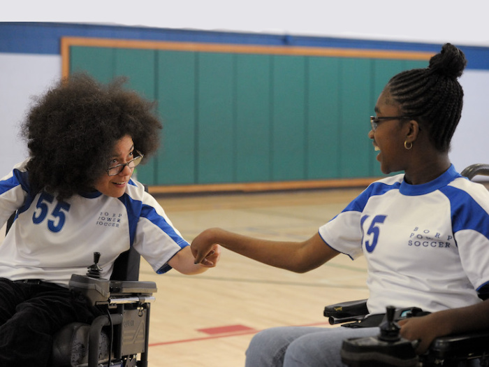 two kids playing indoor wheelchair soccer