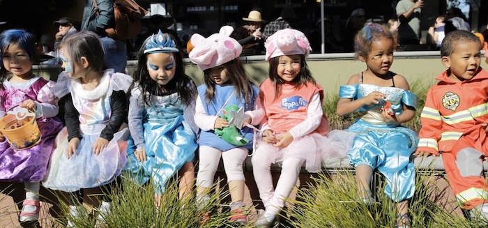 costumed preschoolers sitting on a low wall outside of Peet's on Fourth Street