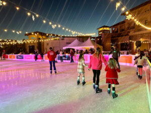 kids Ice skating at dusk with string lights above