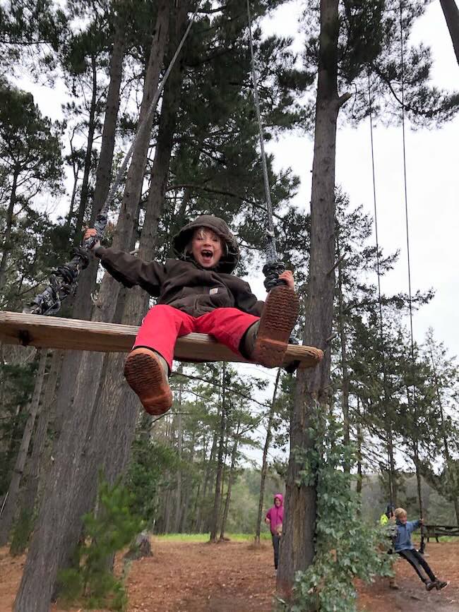 close up of child on a rope and wooden swing