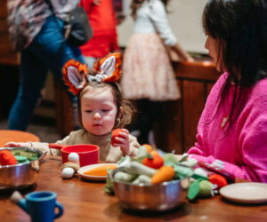 Child playing with pretend garden/kitchen toys near parent