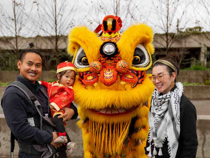 Mom, dad and child pose with Lion Dance at Lunar New Year