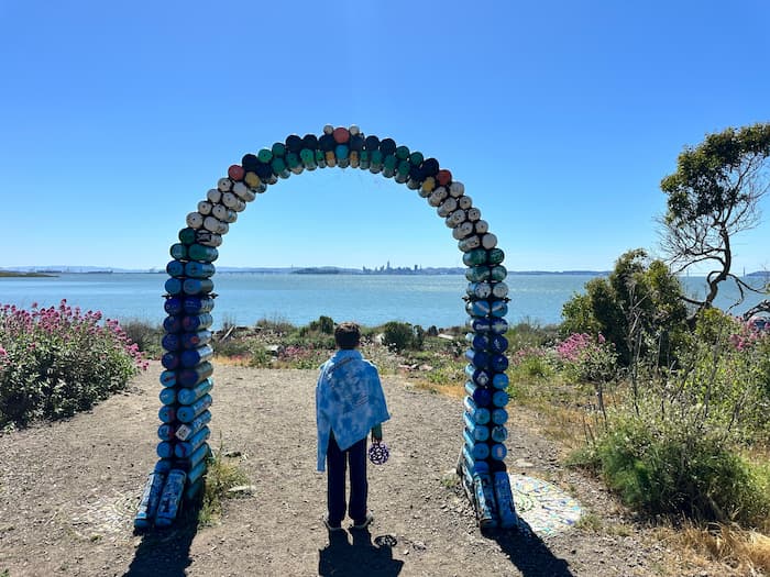 boy standing under arch looking out at the ocean
