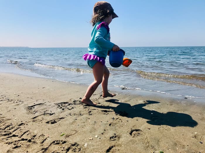 little girl with sand toys at the beach