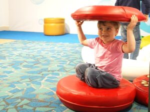 Child crawls inside foam play things at Wobbleland exhibit at Bay Area Discovery Museum.