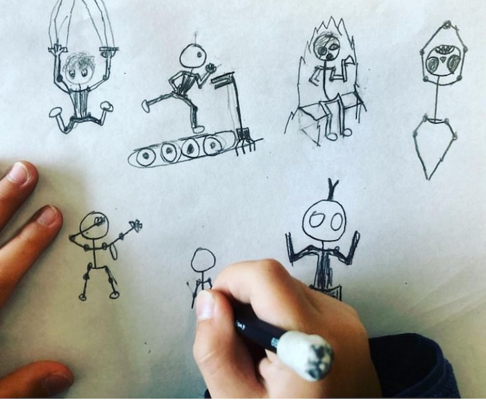 child sketching rough cartoon figures