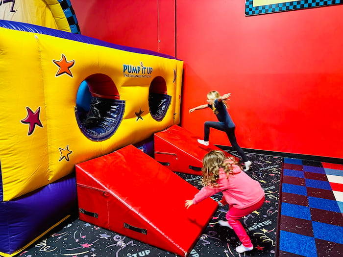 two kids playing on bouncy obstacle course