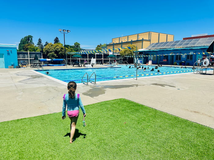 girl walking on grass towards pool