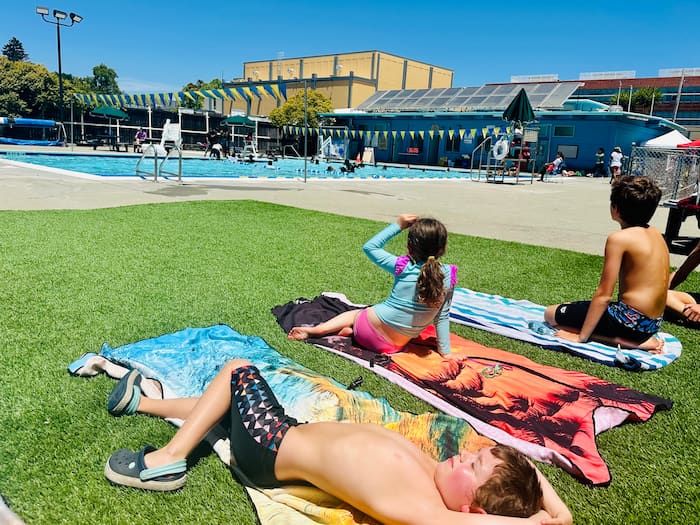 kids laying on grass by pool