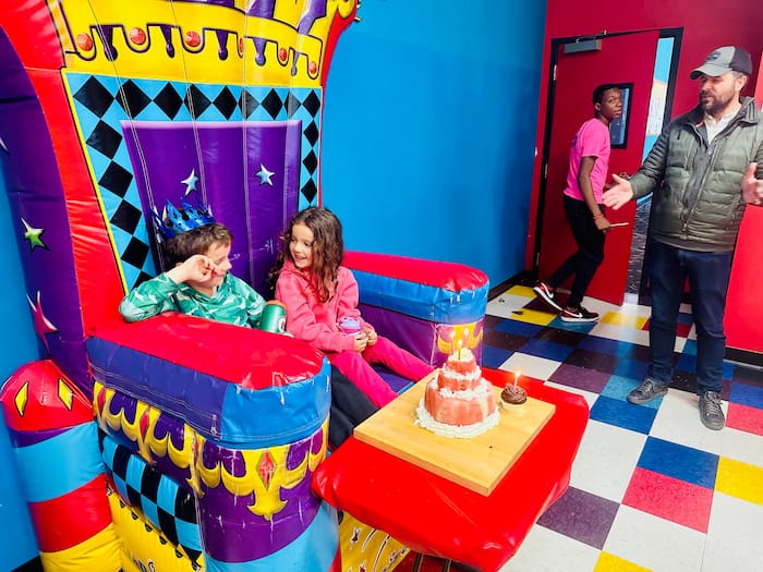 two kids on birthday throne with cake