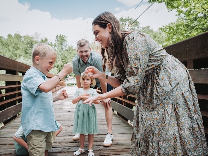 a family of four on a bridge wearing pastel colors