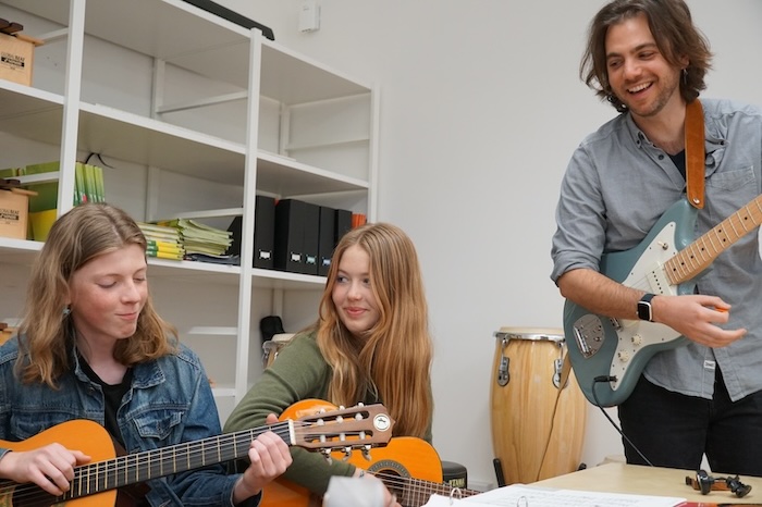 Students and teacher in a music class with guitars