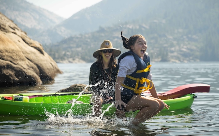 youth jumping in lake near a kayak